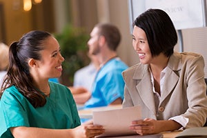 Nurse showing paper to patient and smiling.