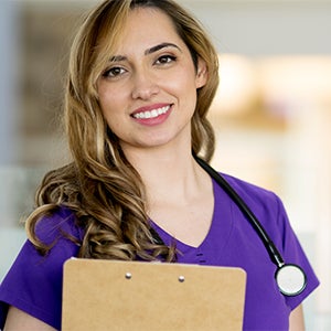 Nurse smiling and holding a clipboard.