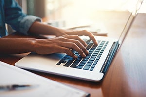 Hands typing on a laptop.